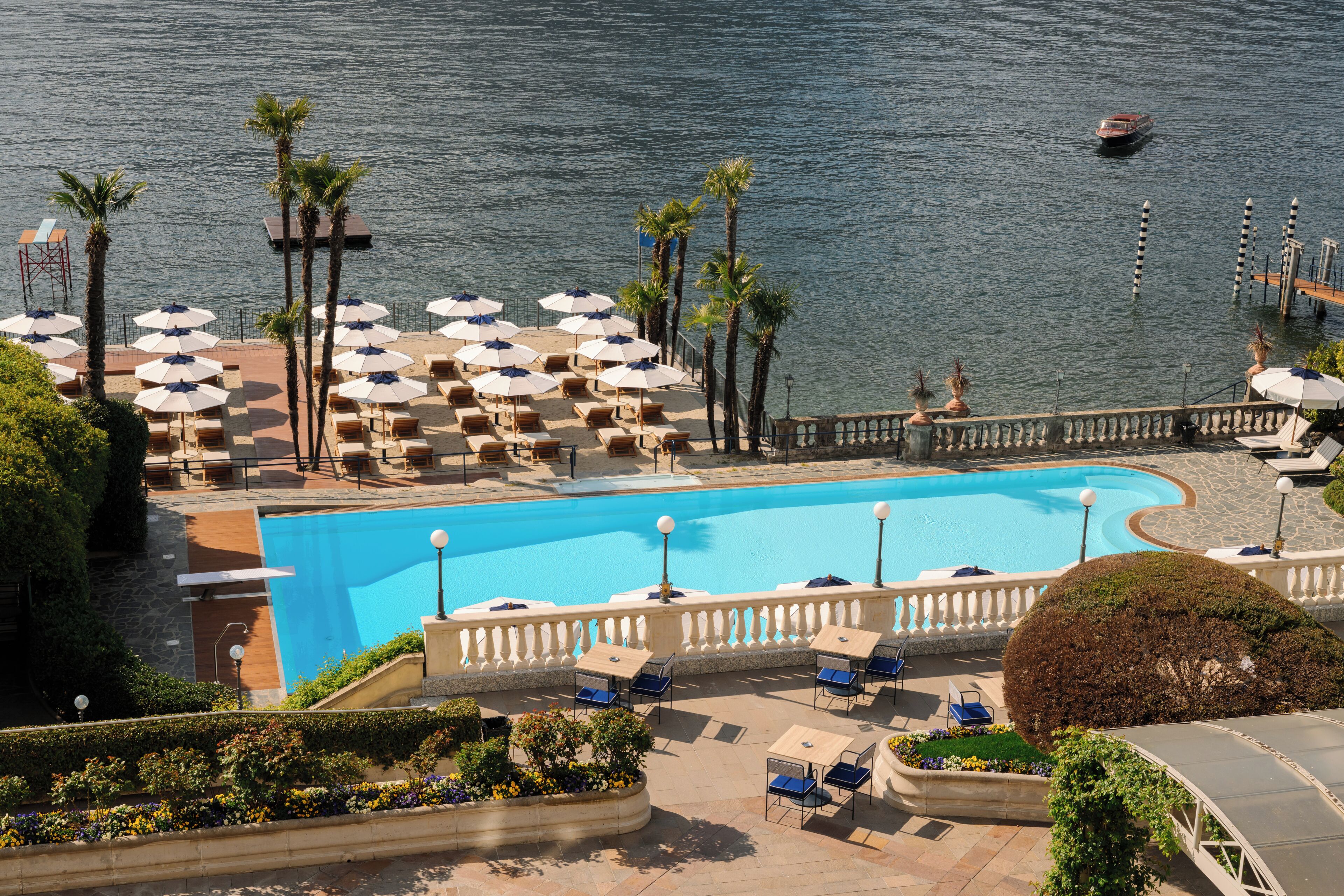 A pool area with lounge chairs and umbrellas, a clear blue pool, and a view of the water.