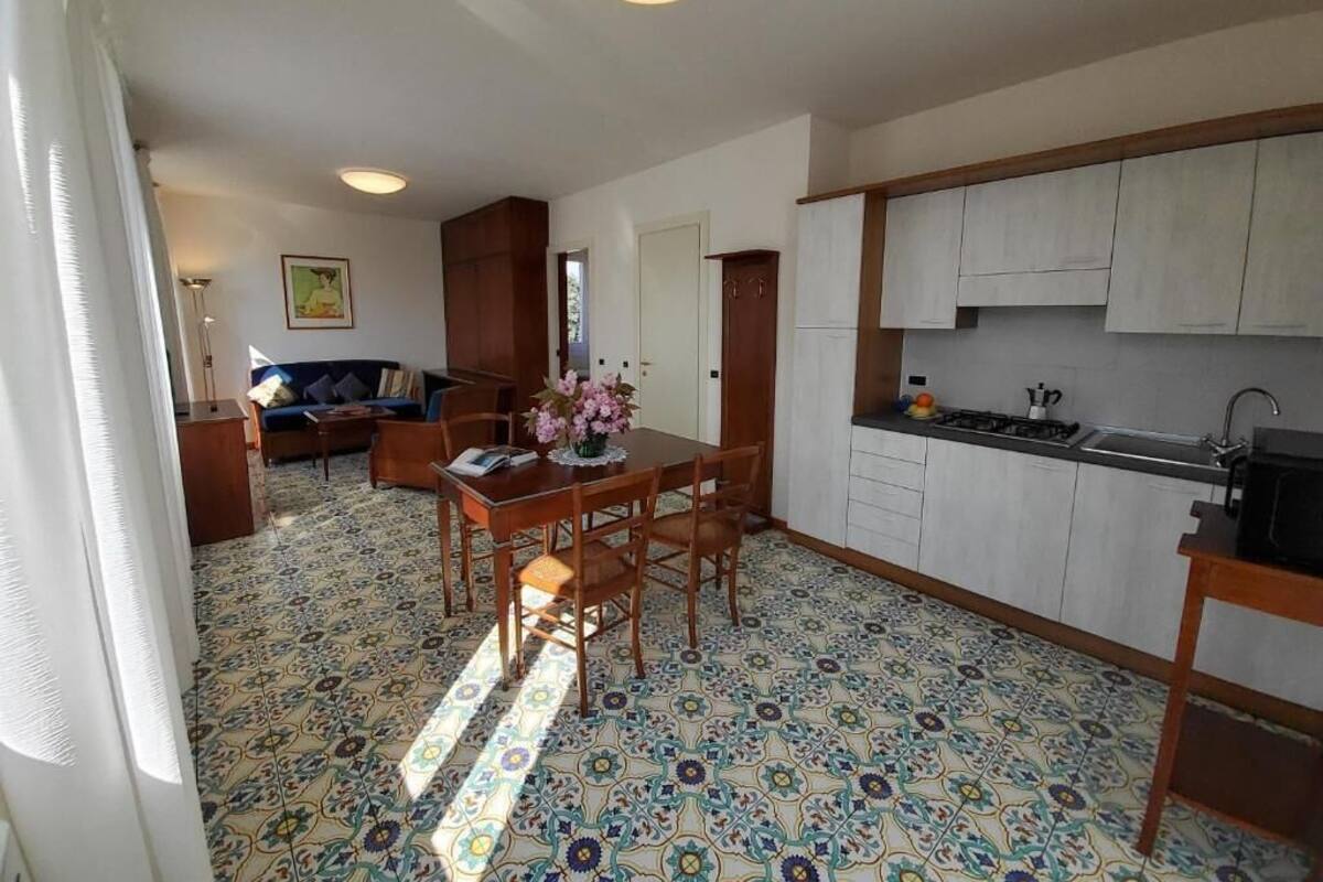 A compact kitchen with white cabinets, a dining area with a table and chairs, and a patterned floor.