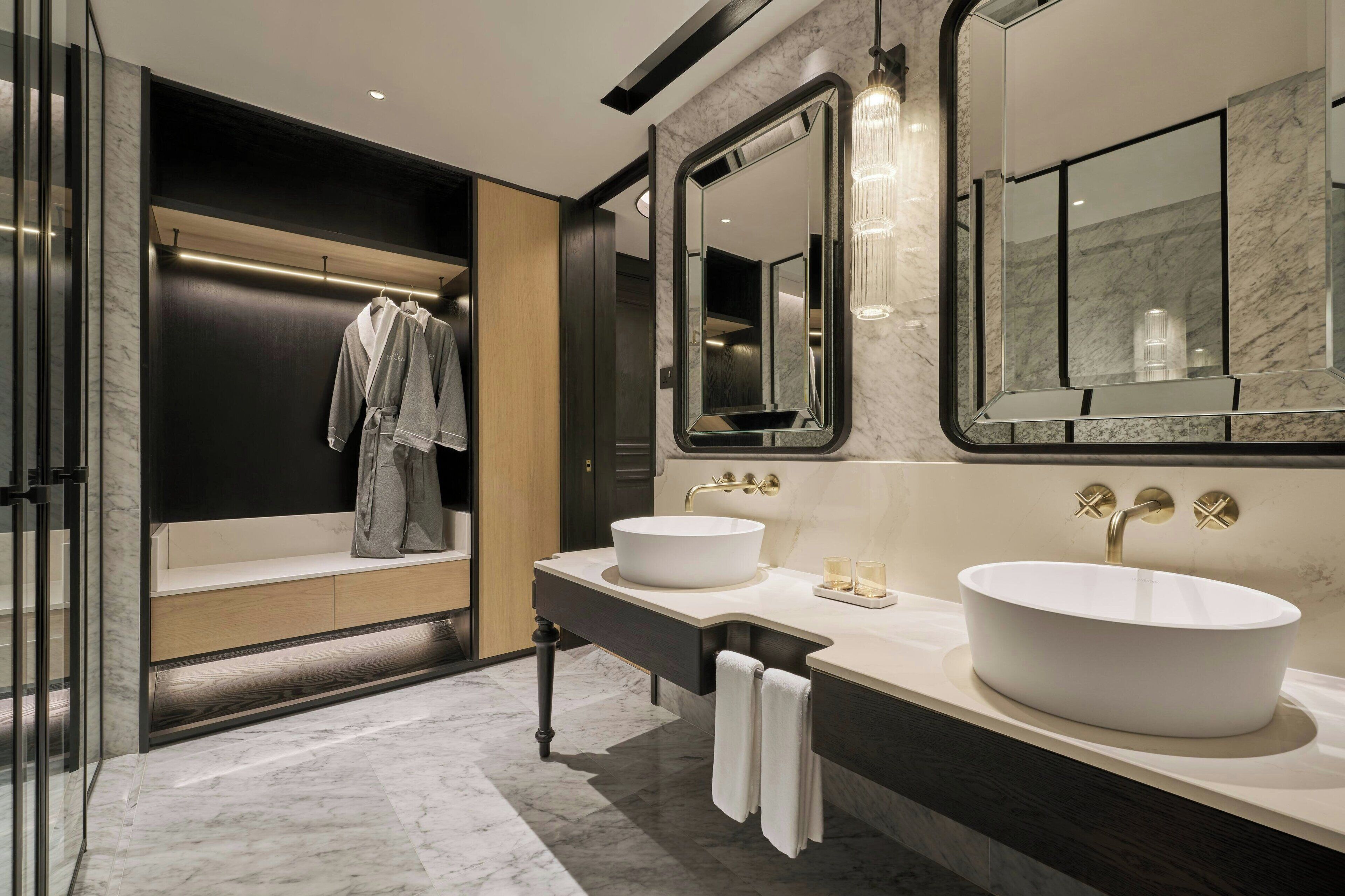 A modern bathroom with a large bathtub, two sinks, and a large mirror.