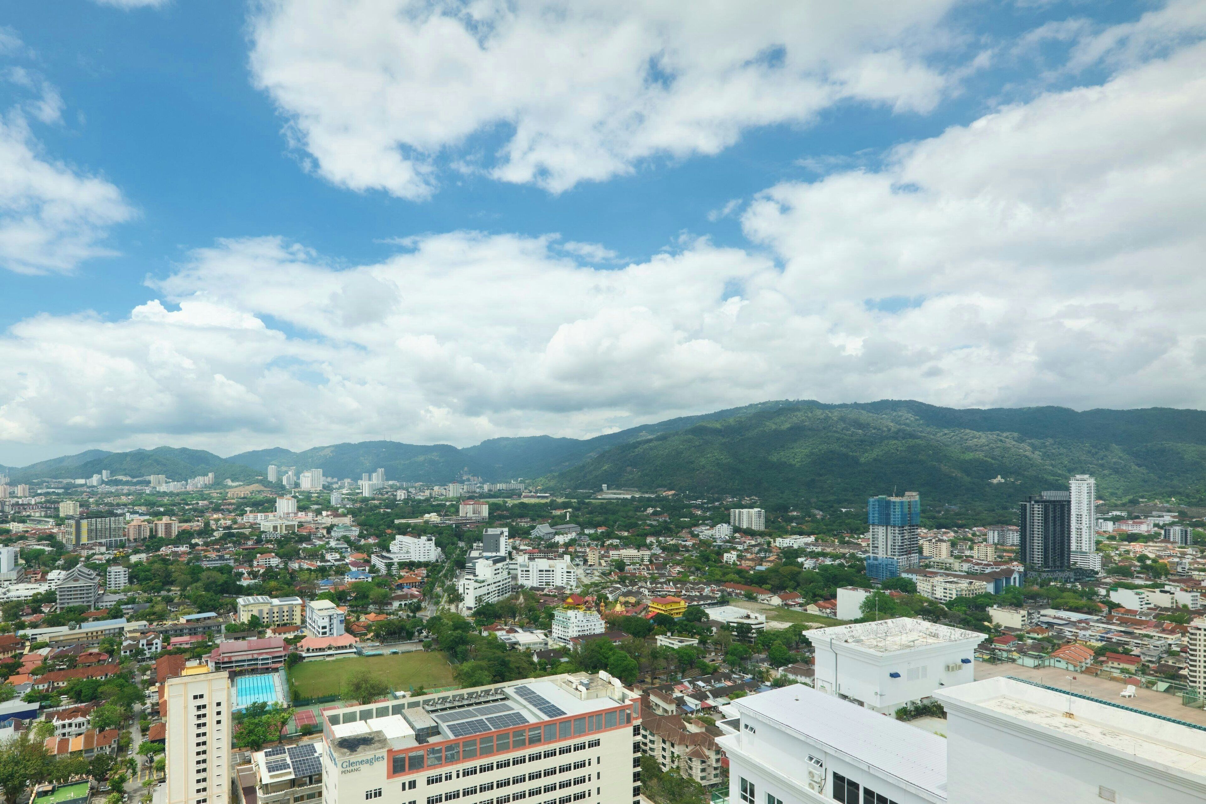 A cityscape with a view of mountains in the background, featuring a mix of residential and commercial buildings.