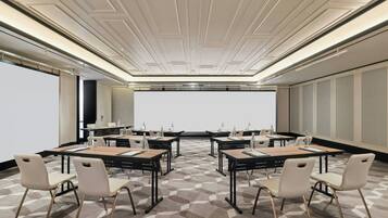 A conference room with a large screen, multiple tables, and chairs arranged for meetings.