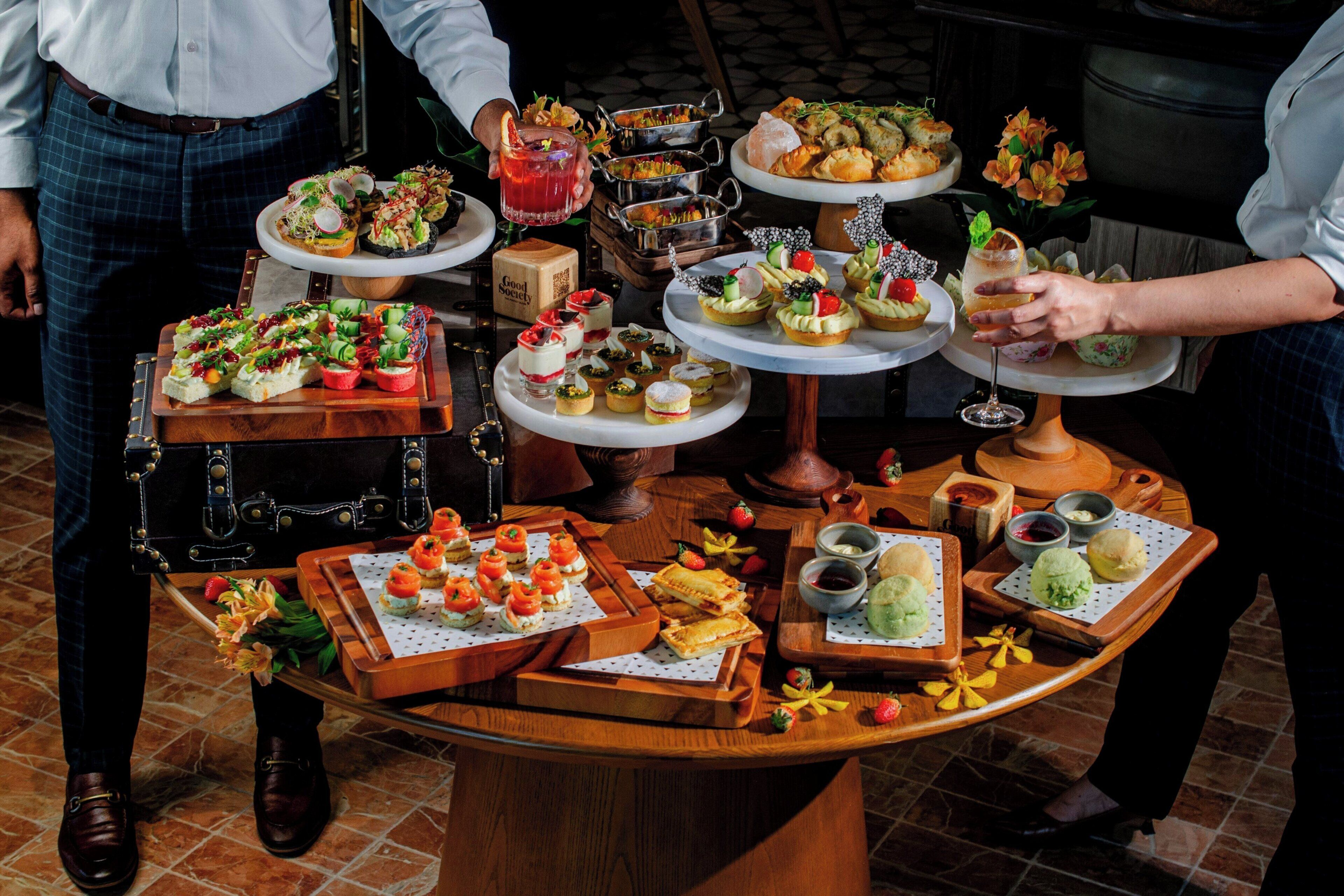 Une table de buffet garnie de différents plats et une personne qui sert des boissons.