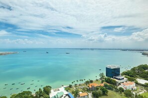 An aerial view of a coastal area with clear blue waters, boats, and buildings including a prominent modern structure. - The Millen Penang, Autograph Collection (George Town)