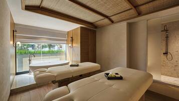 A modern spa room with a large massage table, a separate bathtub, and a shower area.
