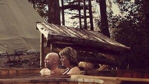 A rustic wooden cabin with a large tent in the background, a wooden bench, and a small table. - Dovrefjell Hotell (Dovre)
