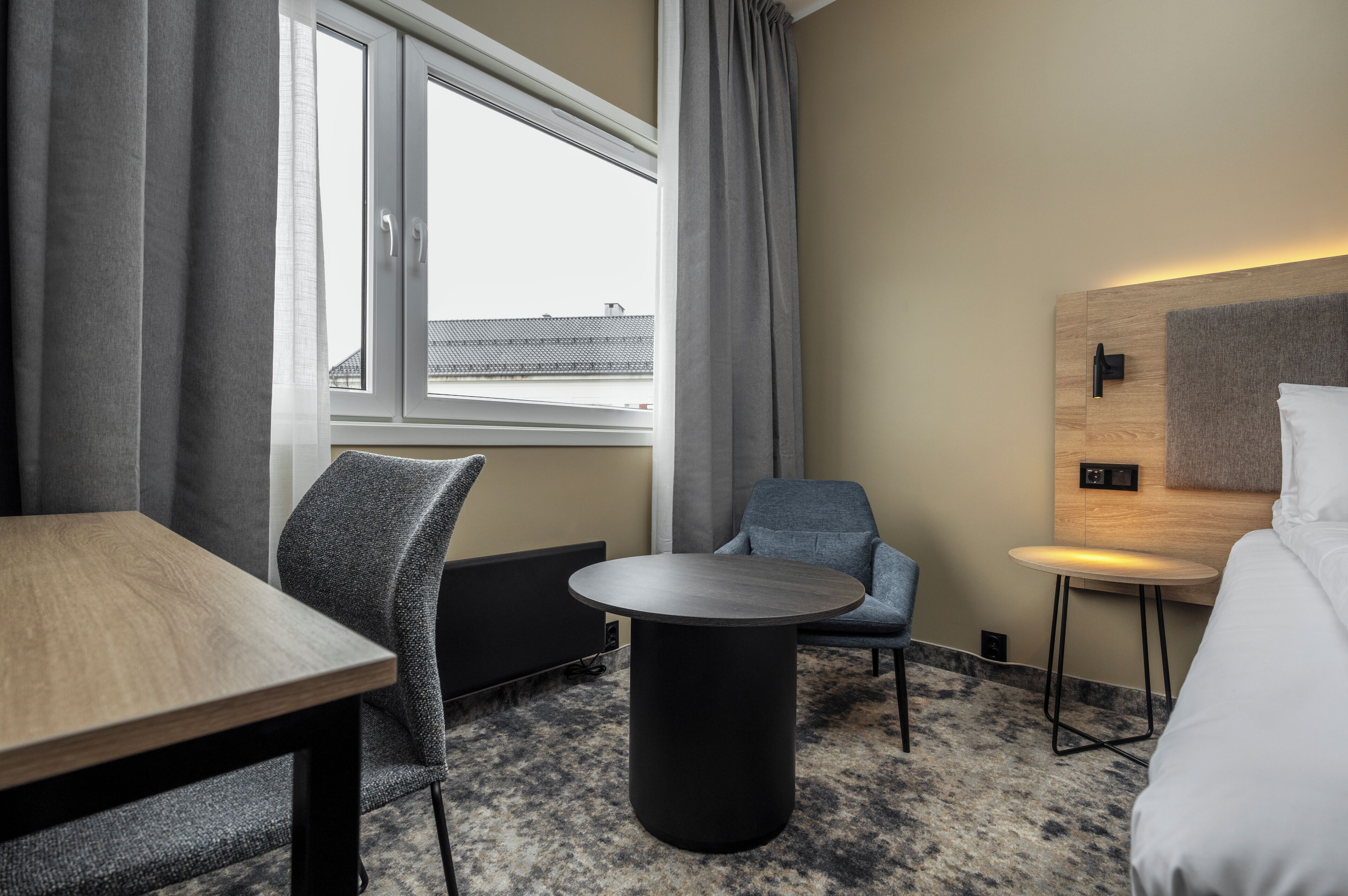 Une chambre d’hôtel avec un lit, une table ronde, une chaise et une petite table d’appoint.