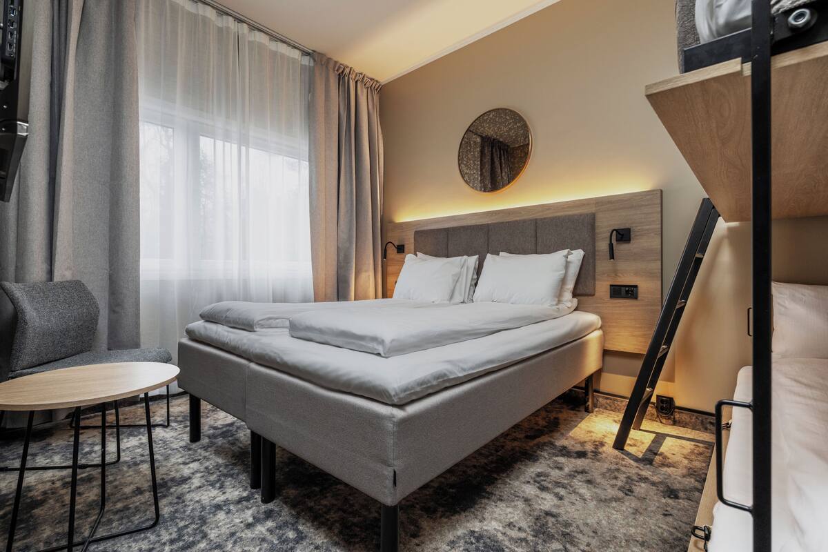A modern hotel room with a large bed, a small round table, and a sofa.