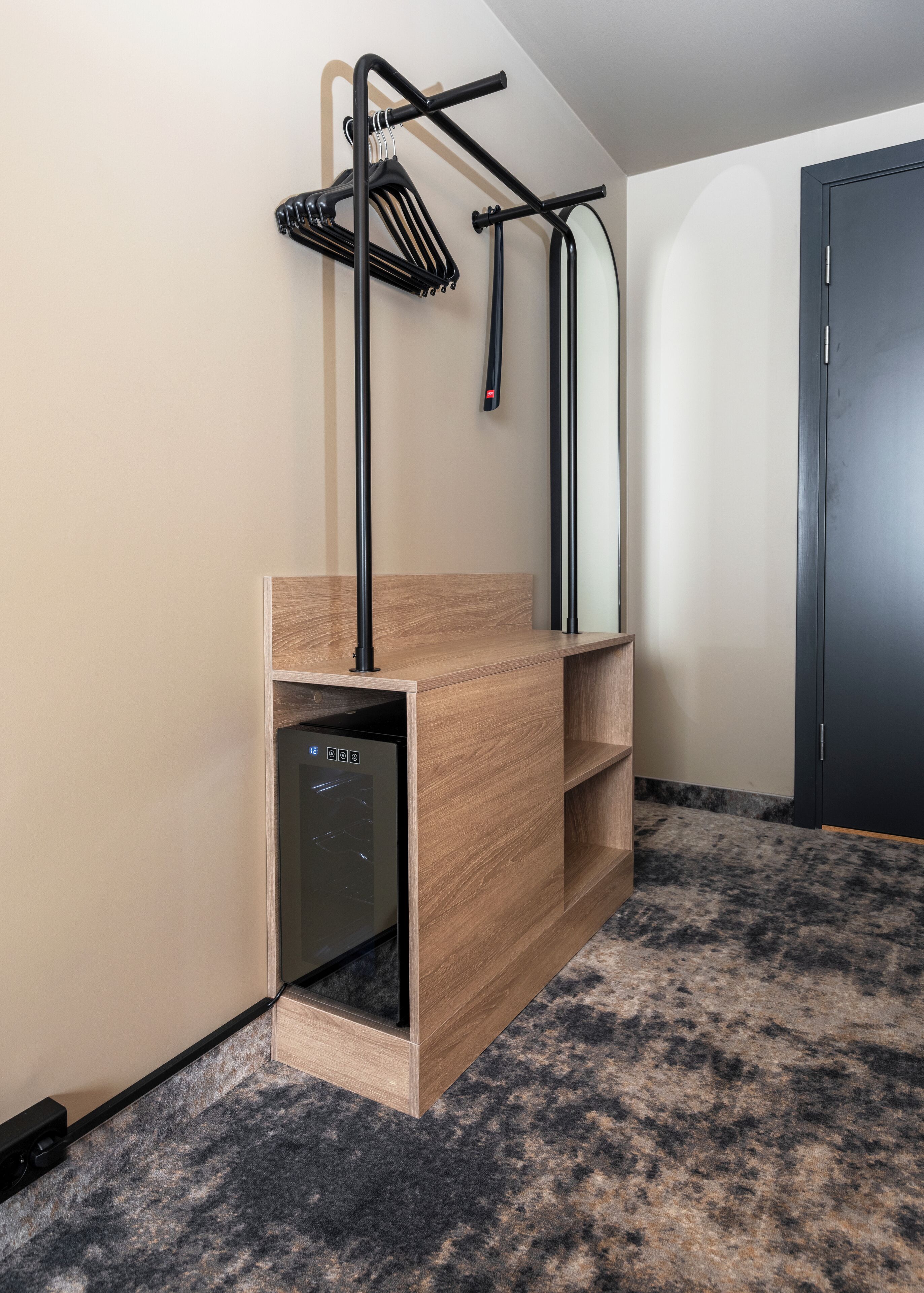 Una habitación compacta con lavavajillas incorporado, un armario de madera y una puerta negra.