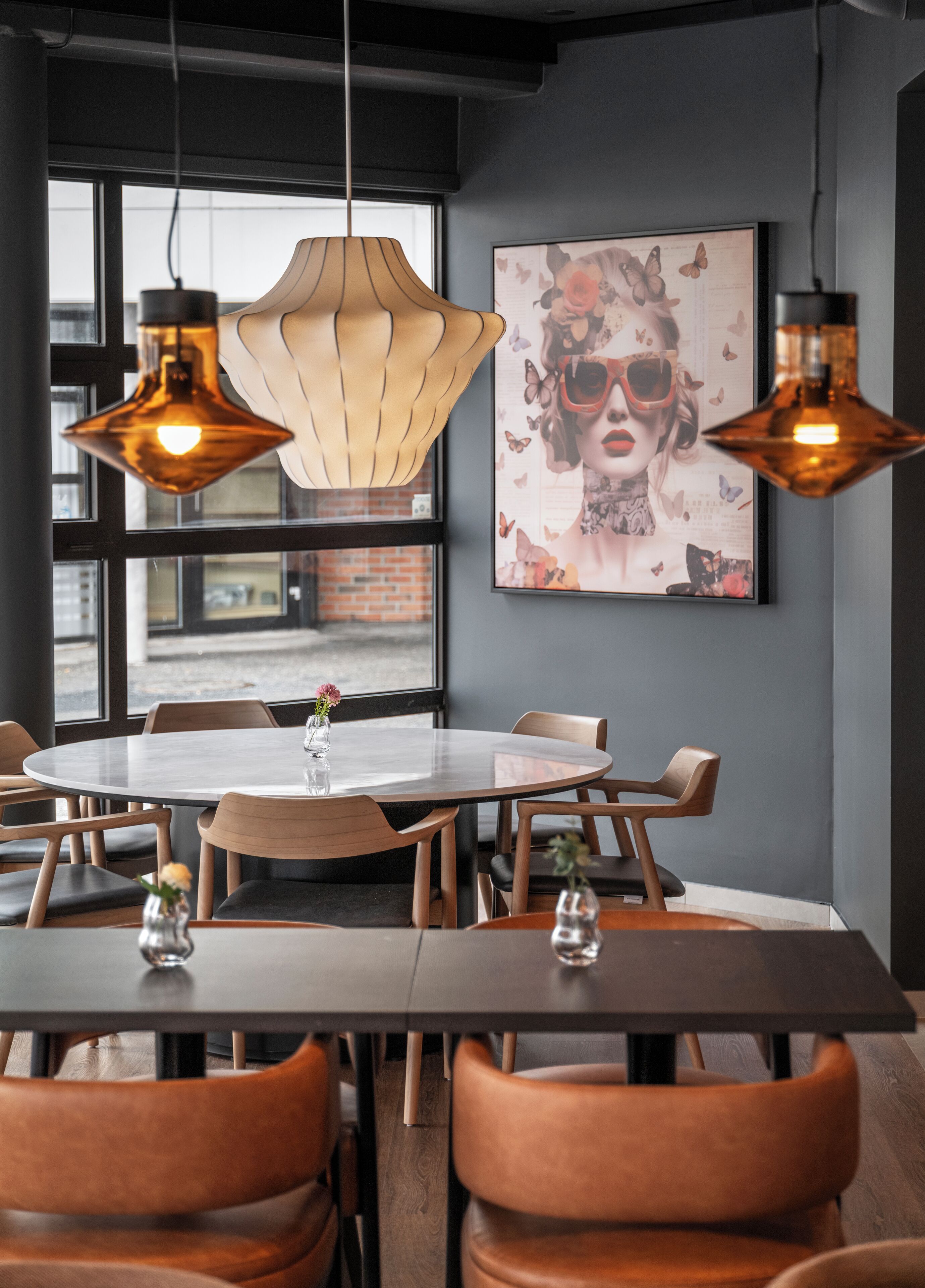 A modern dining area with a round table, wooden chairs, and pendant lighting.