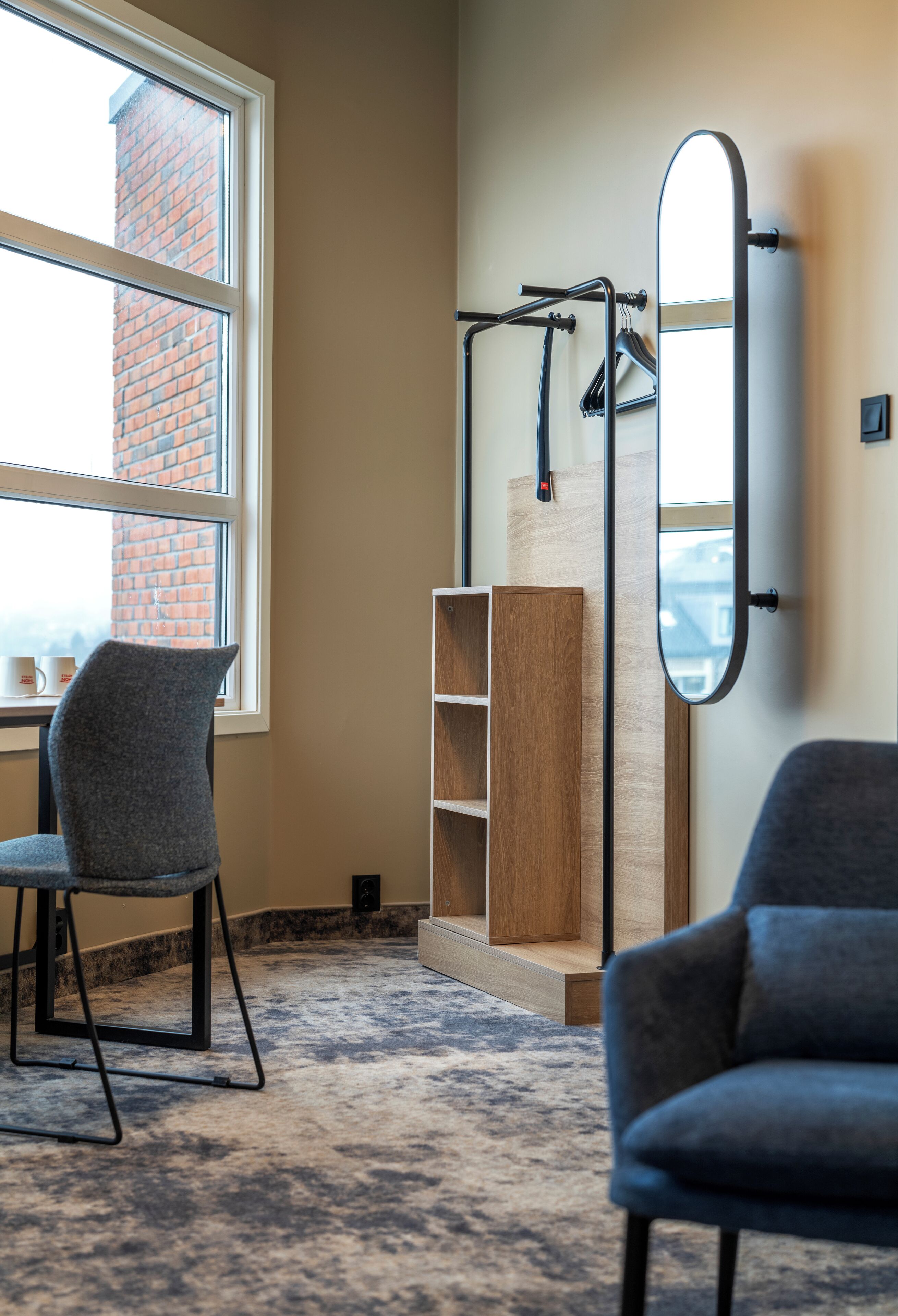 A room with a large window, a wooden cabinet, a mirror, and two chairs.