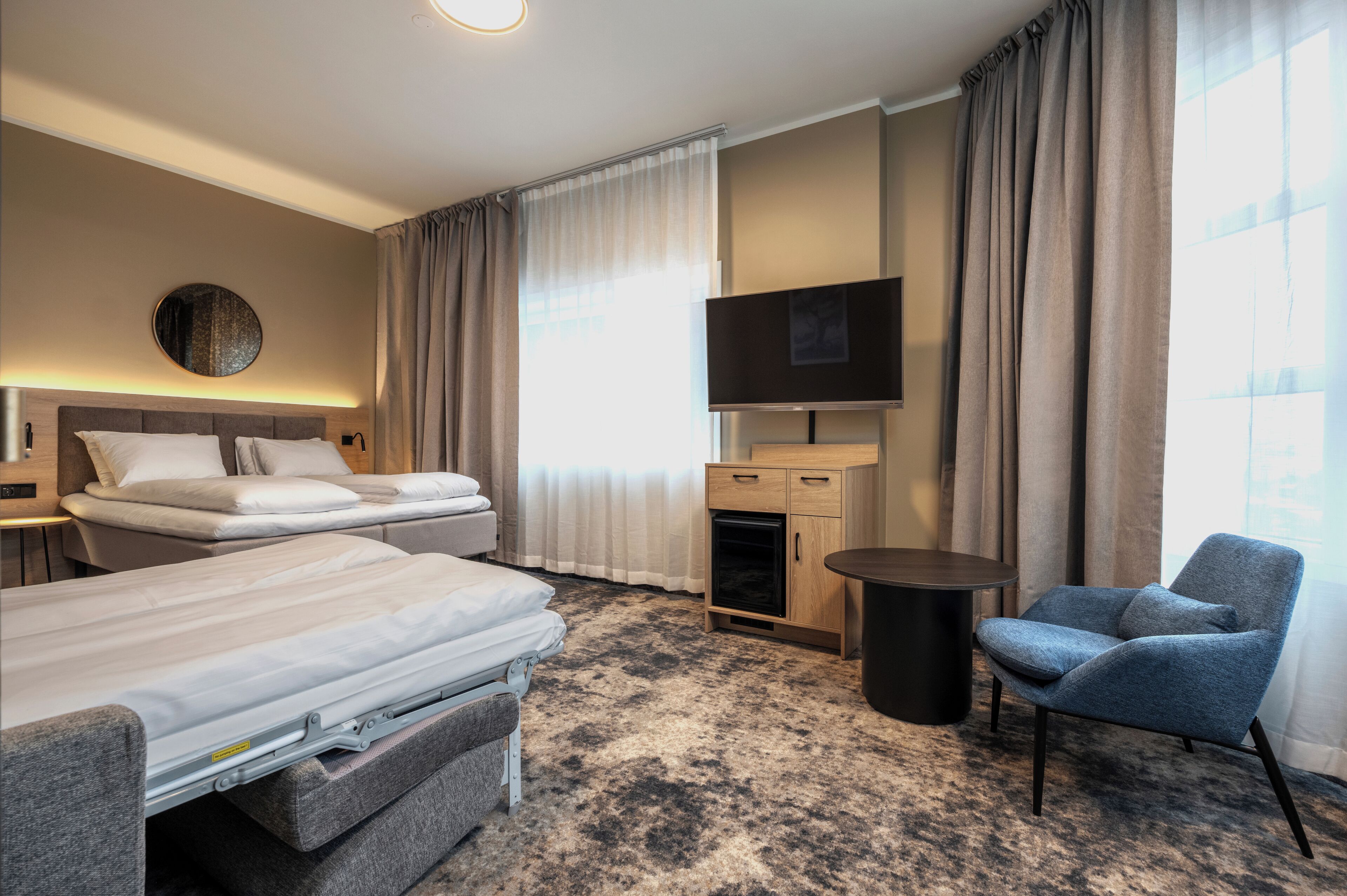 A hotel room with two beds, a TV, a small table, and a chair.
