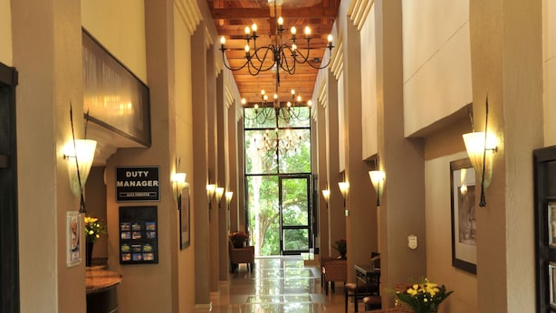 A hotel lobby with a polished floor, wooden ceiling beams, and wall-mounted lighting. - Safari Hotel & Convention Centre (Rustenburg)
