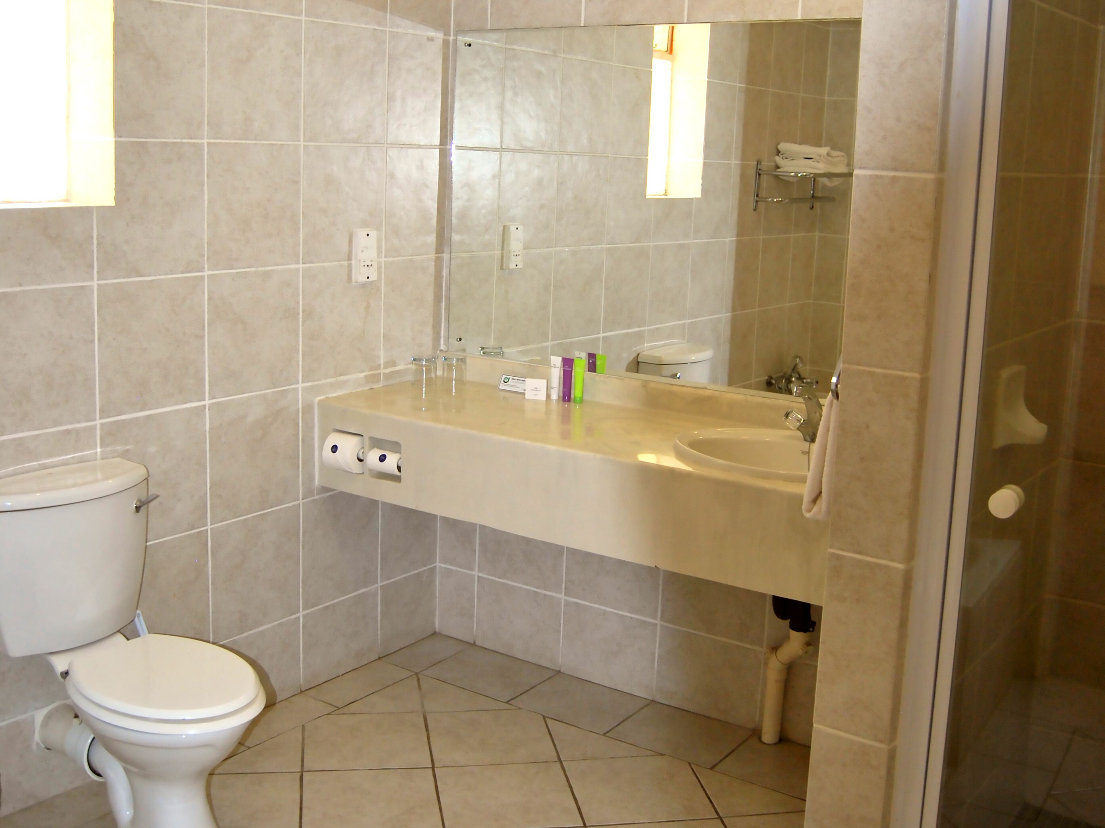 A bathroom with a toilet, sink, mirror, and a shower area.