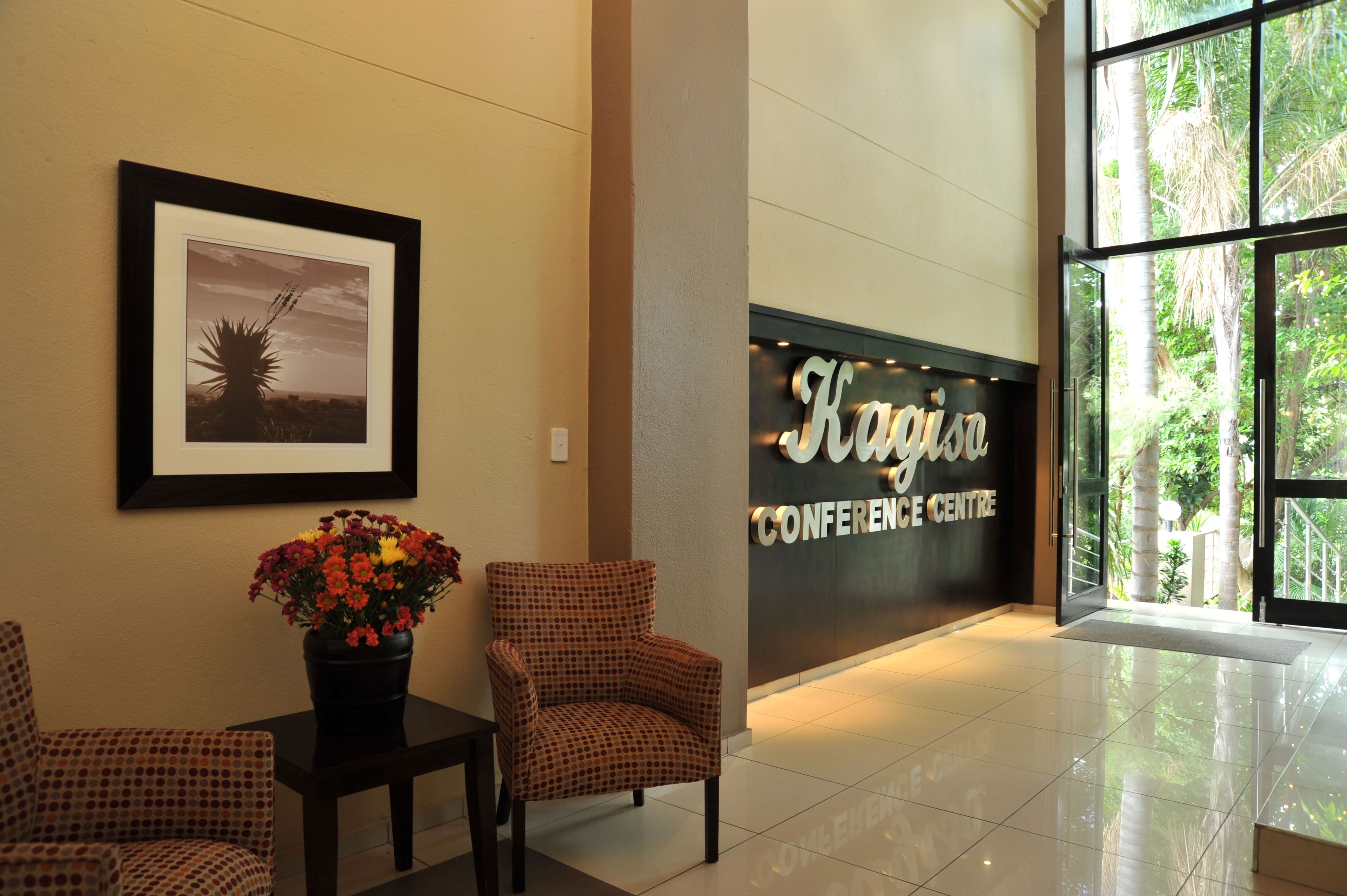 A lobby with framed artwork, a reception desk with a vase of flowers, and a conference center sign.