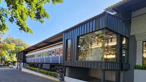 A modern building with a covered outdoor area and a train parked underneath. - Safari Hotel & Convention Centre (Rustenburg)