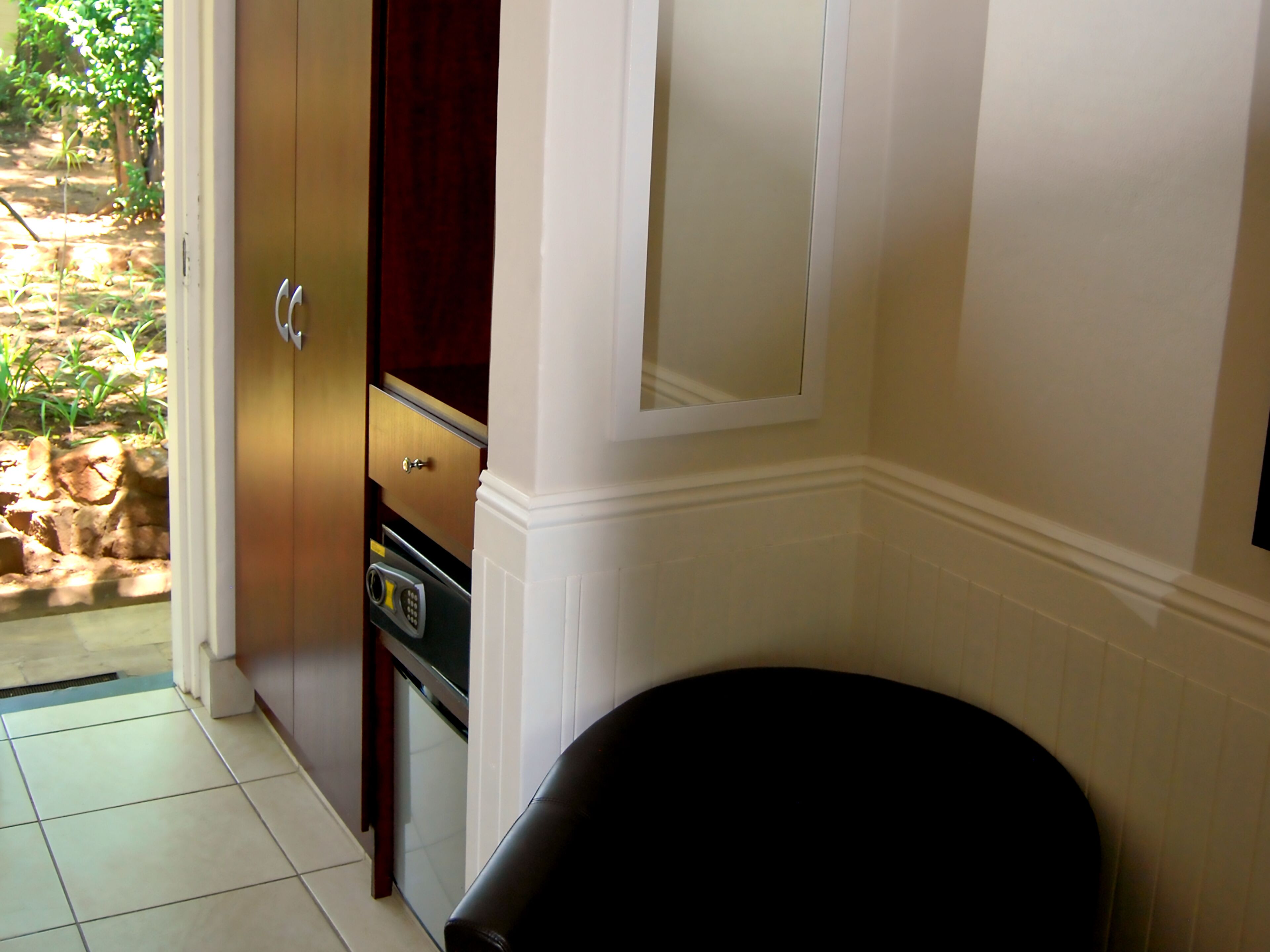 A room with a wooden cabinet, a black chair, and a tiled floor.
