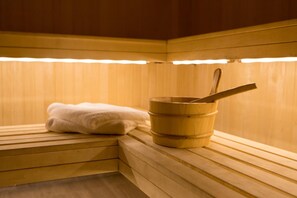Una sauna de madera con un banco, un cubo y una toalla.