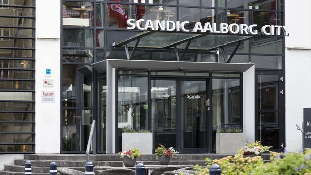 The exterior of Scandic Aalborg City hotel with a modern glass facade, outdoor seating area, and a sign indicating handicap accessibility. - Scandic Aalborg City (Aalborg)