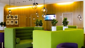 A reception area with green seating, a flat-screen TV, and hanging spherical light fixtures. - Scandic Aalborg City (Aalborg)