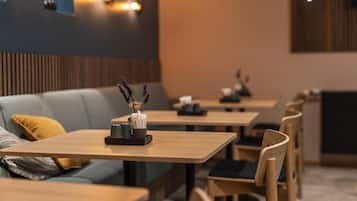 A modern restaurant interior with wooden tables, cushioned seating, and decorative elements on the tables.
