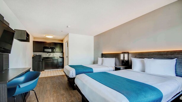 A hotel room with two beds, a desk, and a kitchenette. - Studio 6 Extended Stay - Ocean Springs, MS (Ocean Springs)
