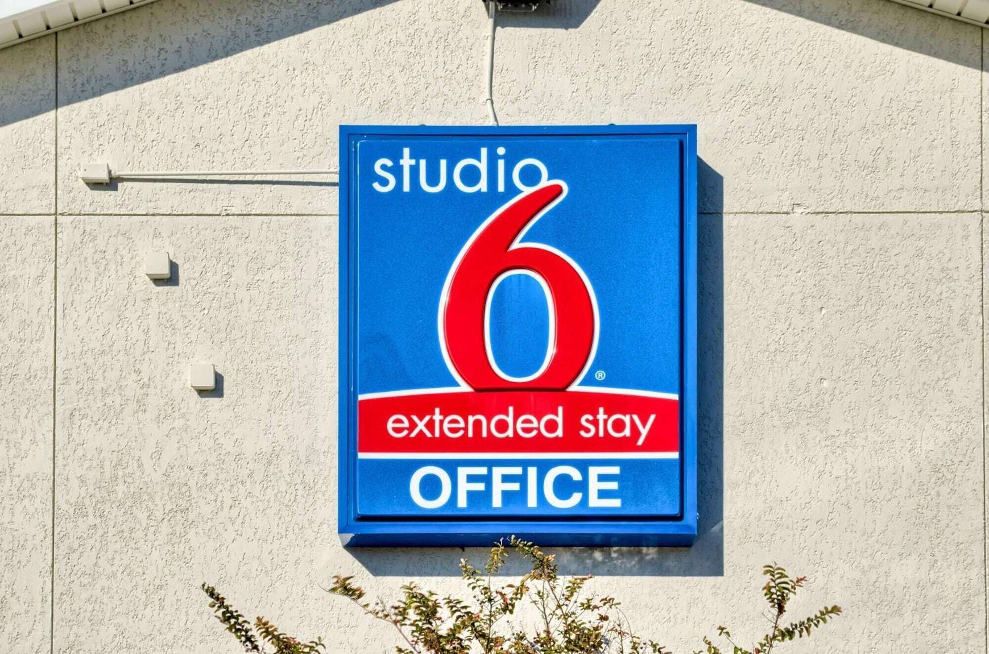 Een blauw bord met de tekst 'studio 6 extended stay office' op een gevel.