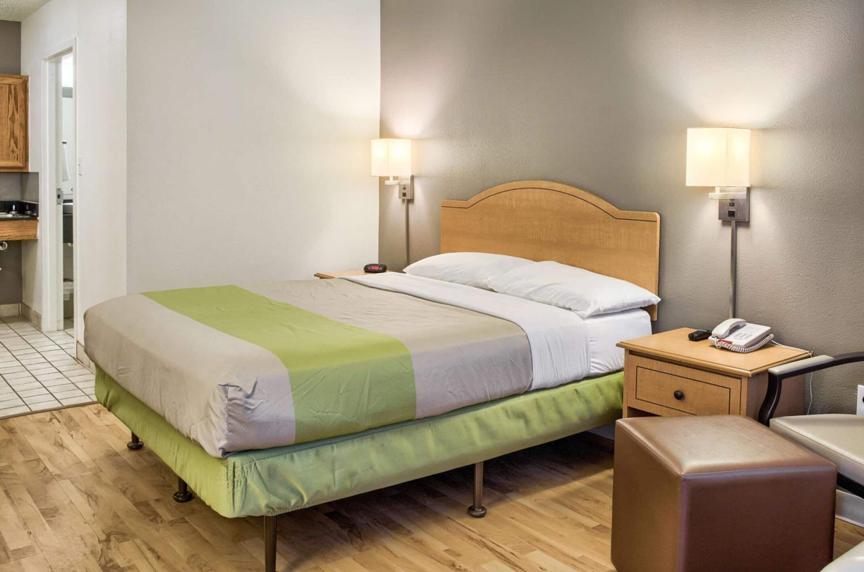 A neatly arranged hotel room with a bed, bedside lamps, a bedside phone, and a small wooden nightstand.