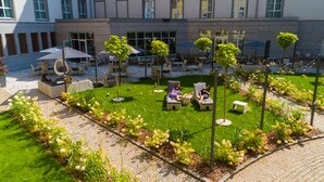 A courtyard with outdoor seating, greenery, and a building in the background. - Radisson Blu Hotel, Wroclaw (Wroclaw)