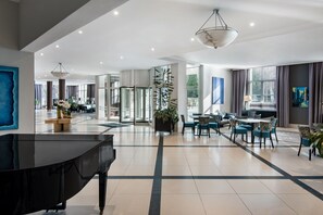 A spacious hotel lobby with a grand piano, modern furniture, and large windows offering views of the outdoors. - Radisson Blu Hotel, Wroclaw (Wroclaw)