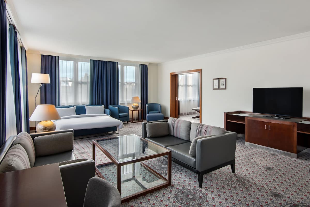 Una habitación de hotel con una cama, un sofá, un televisor y una mesa de centro.