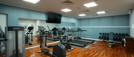 A gym with treadmills, elliptical machines, weight benches, and dumbbells.