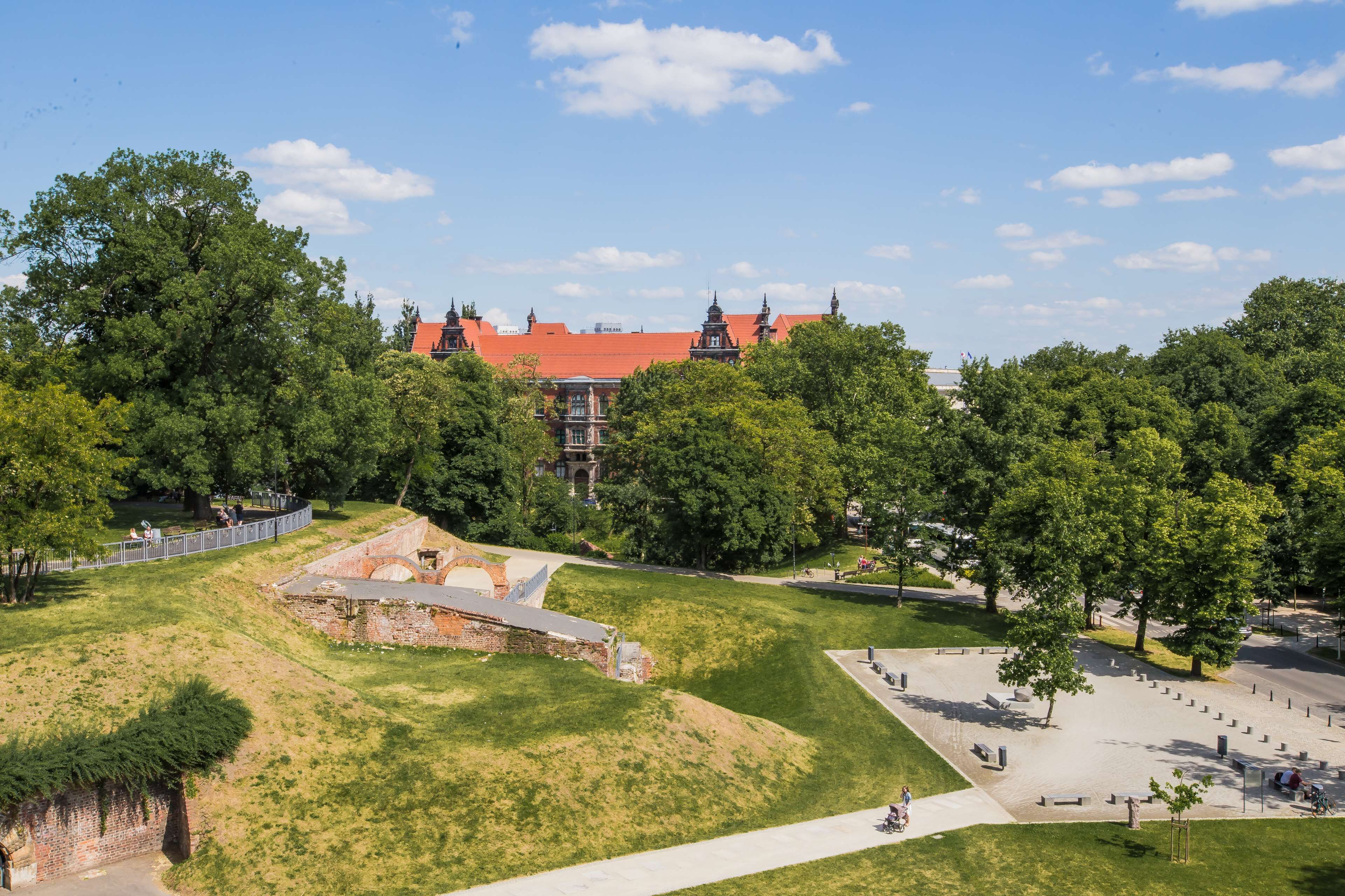 A park with a historical building, pathways, and open grassy areas.