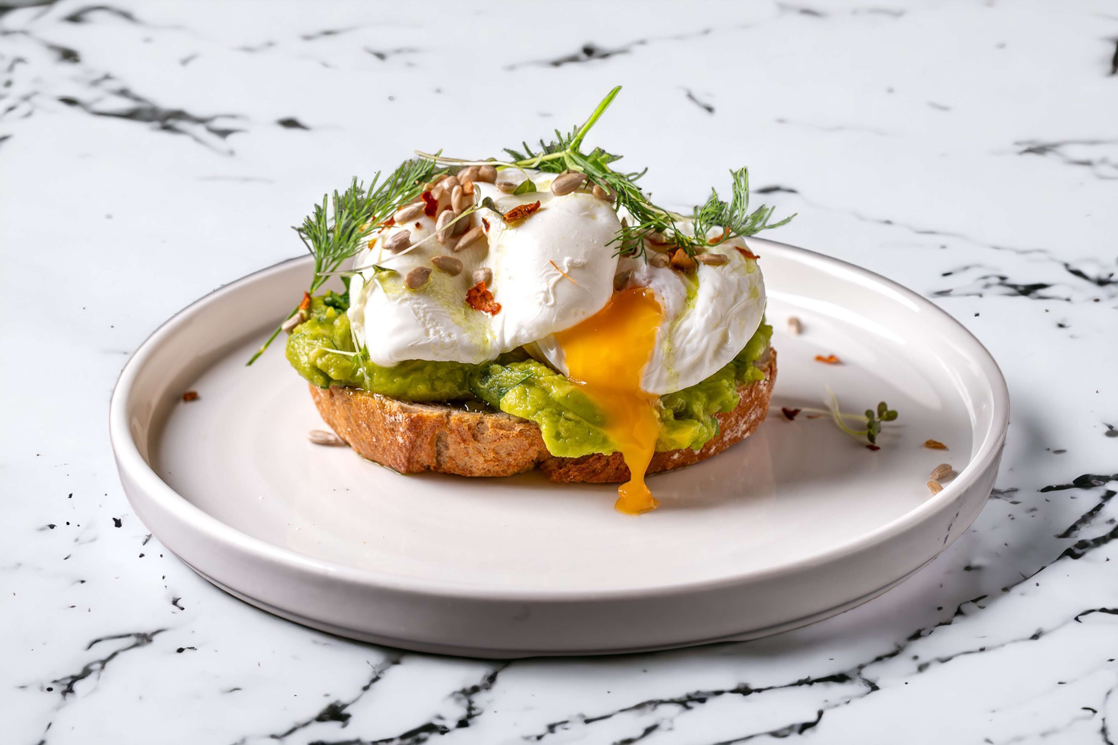 Un plat de petit-déjeuner servi dans une assiette blanche, le tout posé sur un fond en marbre.