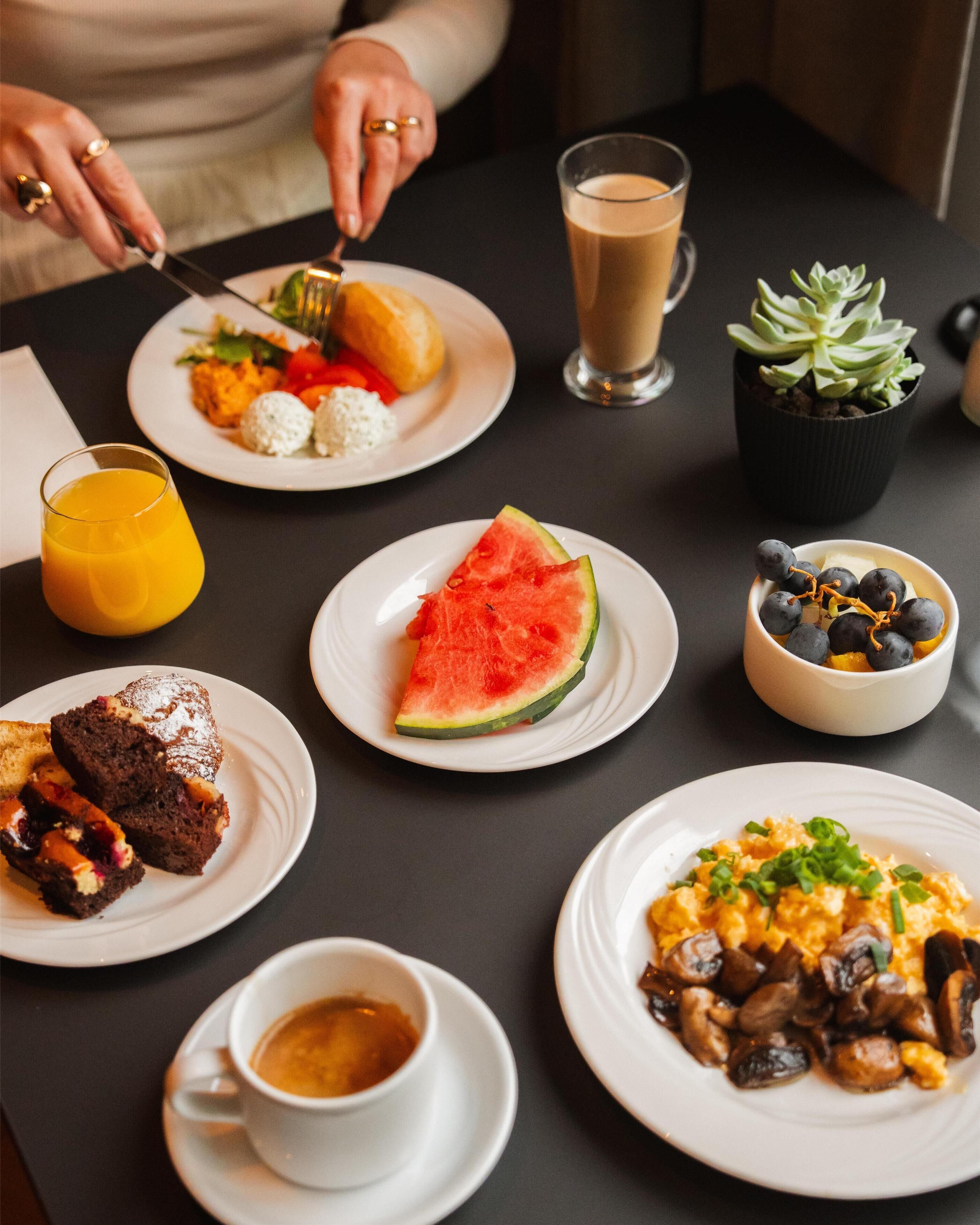 A table with various breakfast items including toast, eggs, a slice of watermelon, and a cup of coffee.