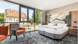 A hotel room with a large window, a bed, a chair, a small table, and a mural on the wall. - Hotel zur Post (Ismaning)
