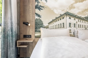A bedroom with a bed, a wall-mounted light, and a control panel. - Hotel zur Post (Ismaning)