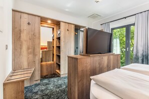 A bedroom with a bed, a TV on a wooden stand, a closet with a mirror, and a window with curtains. - Hotel zur Post (Ismaning)