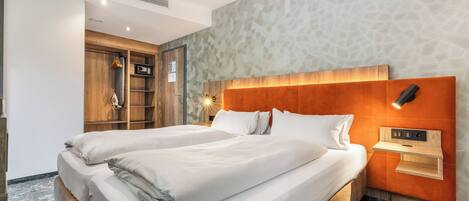 A double bed with a wooden headboard, a bedside table with a lamp, and a wardrobe with a mirror.