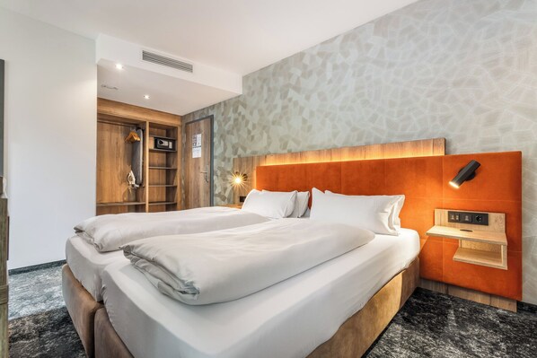 A double bed with a wooden headboard, a bedside table with a lamp, and a wardrobe with a mirror. - Hotel zur Post (Ismaning)