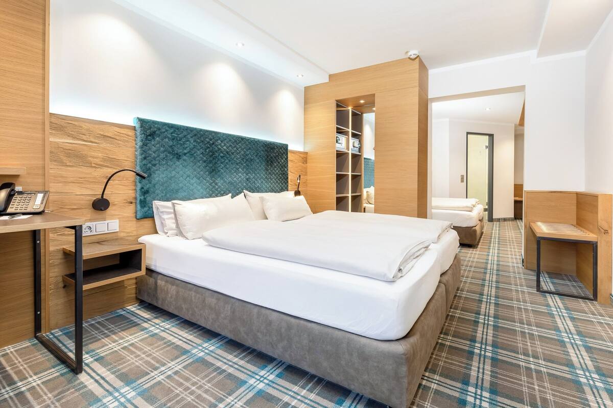 A hotel room with a bed, bedside table, phone, and a headboard.