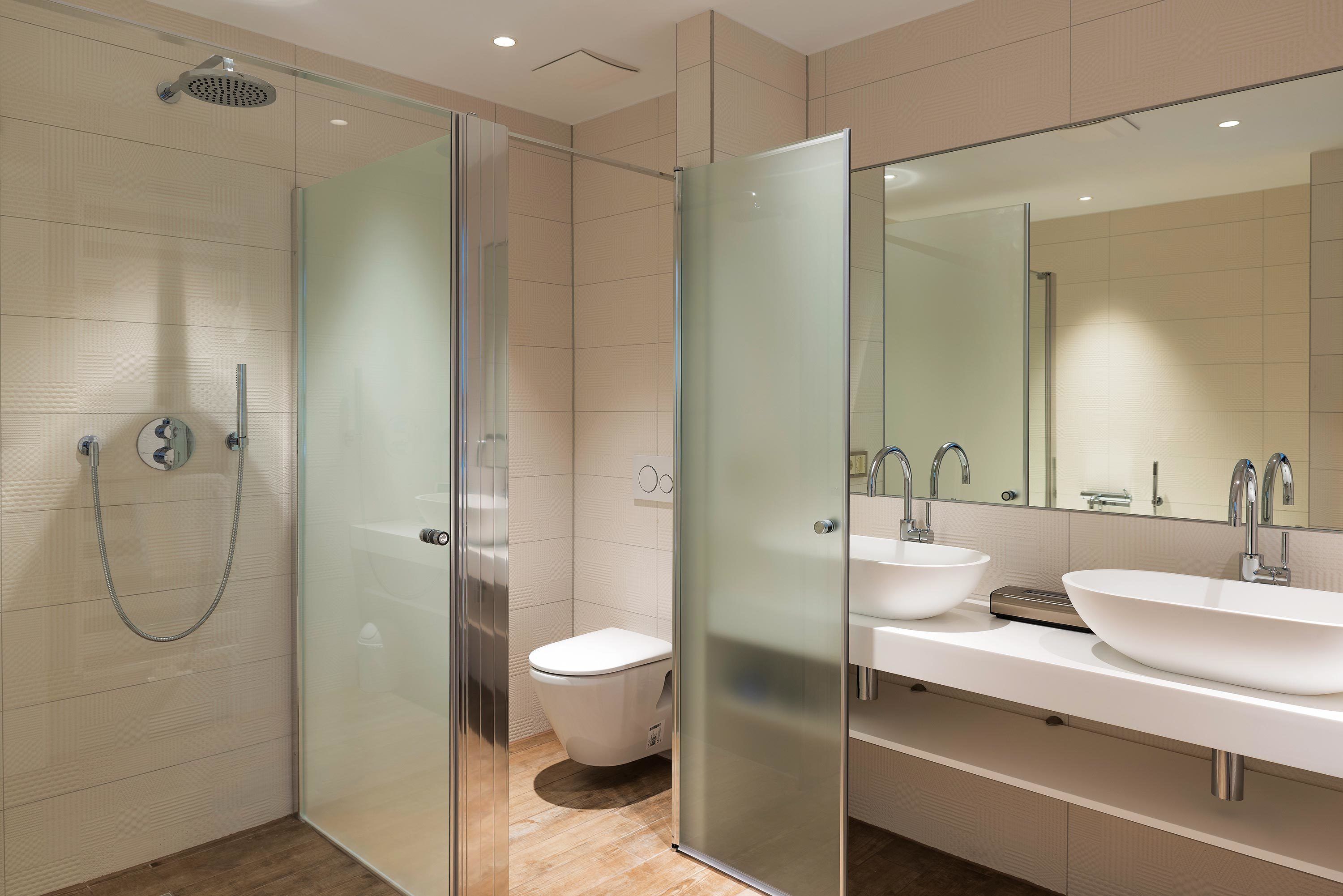 Un baño moderno con ducha de vidrio, inodoro y tocador doble.