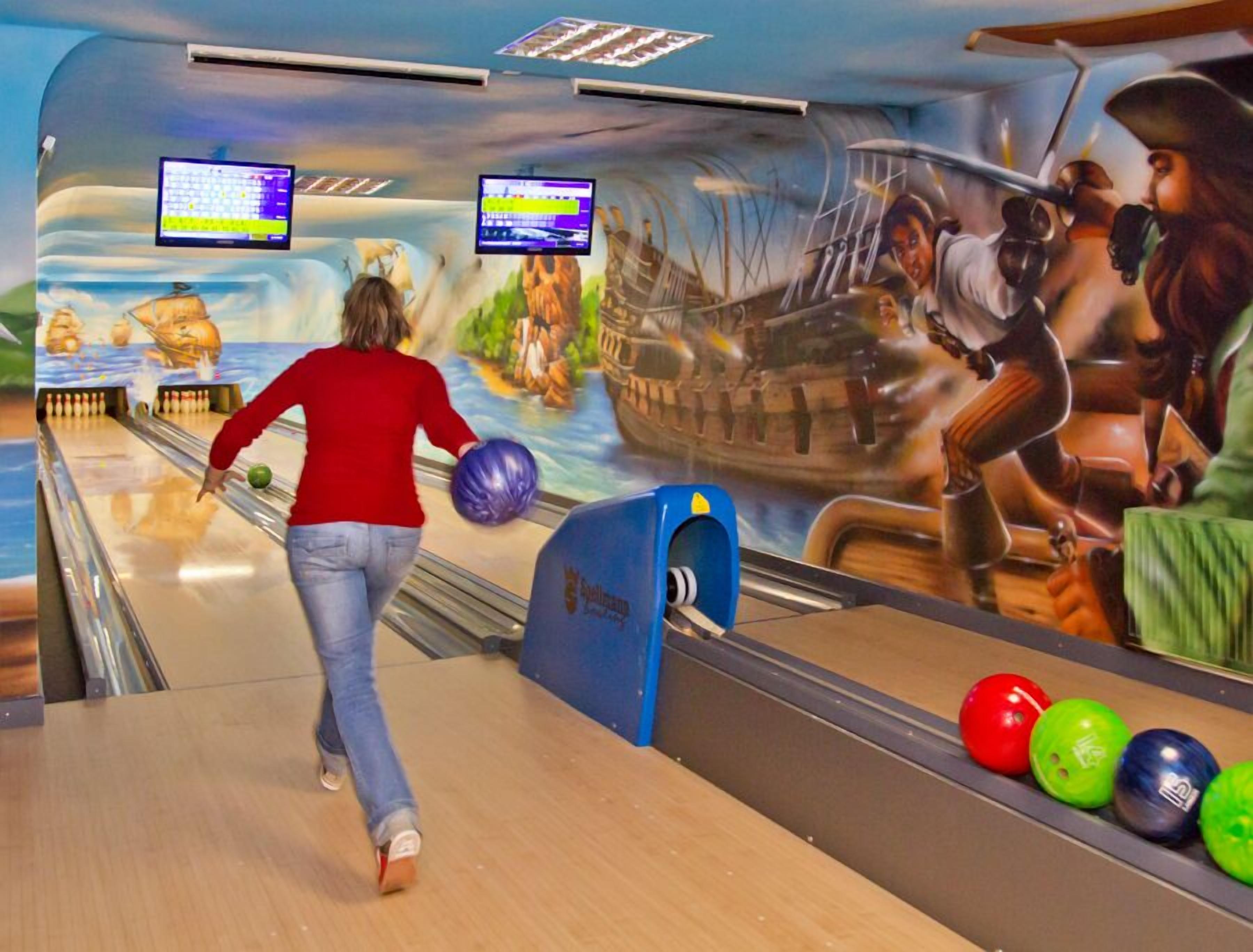 Bolera con un mural de un barco pirata y una mujer lanzando los bolos.