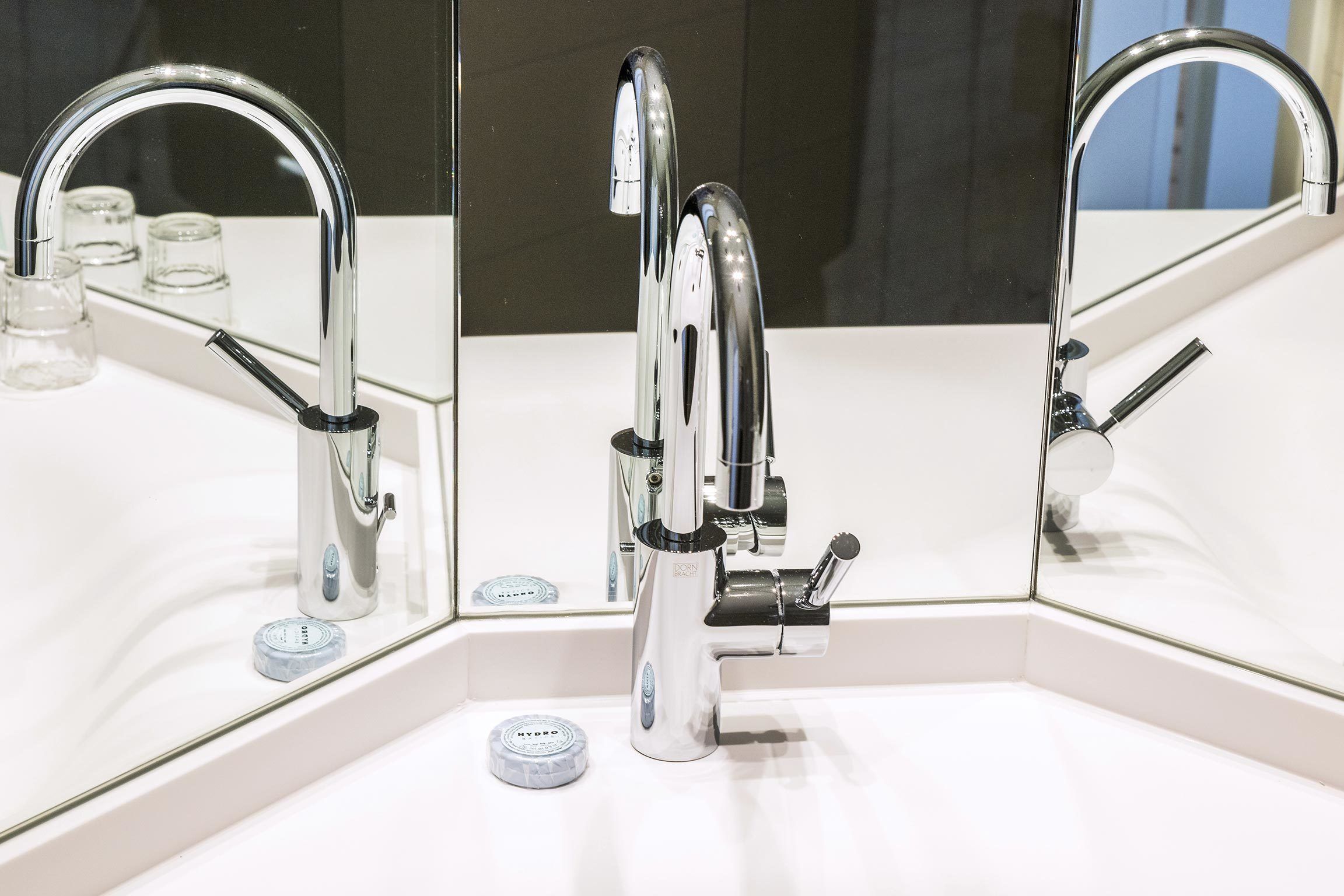 A modern bathroom with a chrome faucet, a mirror, and a white sink.