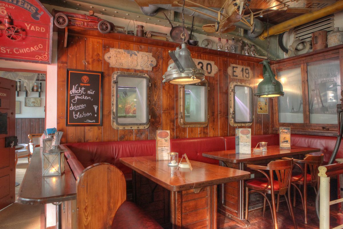 Interior de restaurante de estilo vintage con paredes de madera, señalización antigua y ventanas con marco de metal.