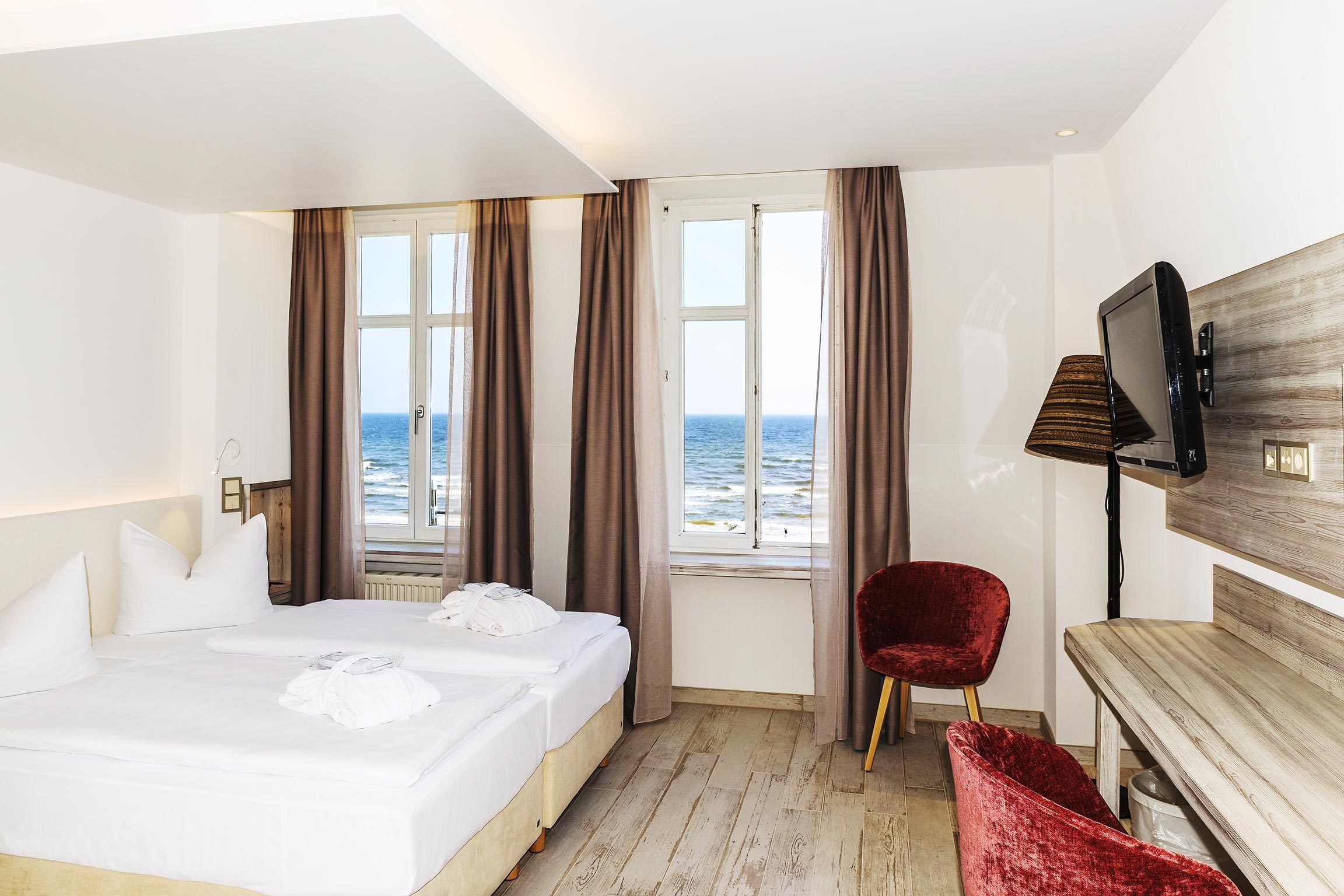 Une chambre d’hôtel avec un lit, une télévision, un bureau et une vue sur la mer.