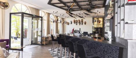 Zona de bar moderna con una barra de mármol negro, taburetes negros y una alfombra estampada.