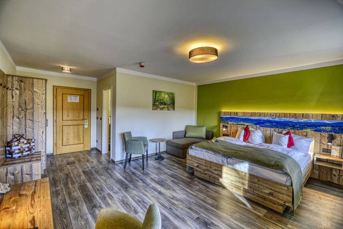A room with a bed, a small table, two chairs, and a wooden wardrobe.