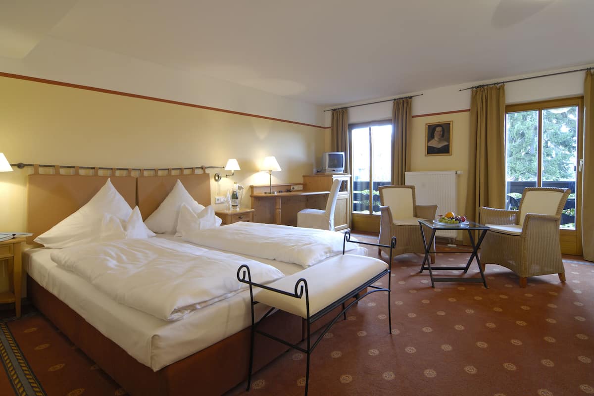 A hotel room with two beds, a desk, a chair, and a television.