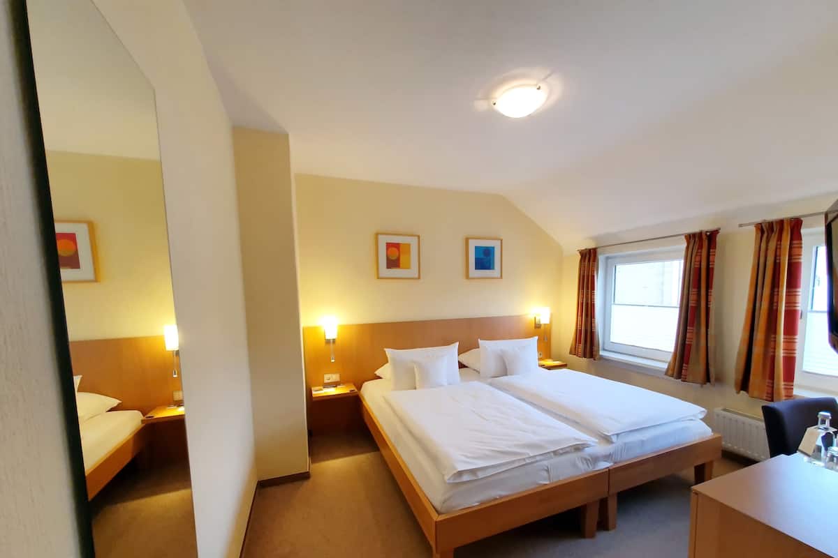 Una habitación de hotel con una cama grande, mesitas de noche, un escritorio y una ventana con cortinas.
