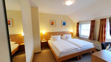 Una habitació d'hotel amb un llit gran, taules de nit, escriptori i una finestra amb cortines.